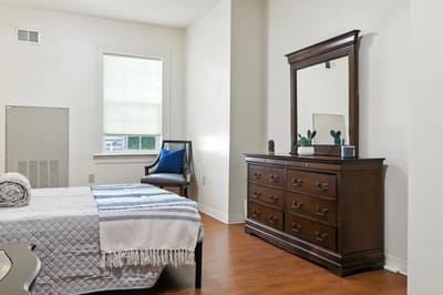 Well-furnished private resident room with a dresser and seating area