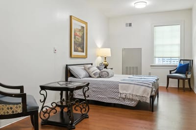 A well-furnished resident room with a bed and artwork