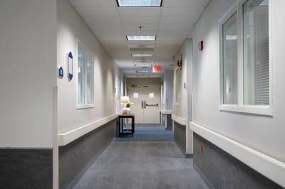 A hallway with a table and lamp in an assisted living facility