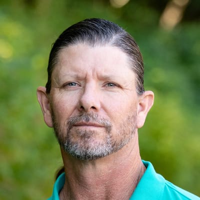 A man with a beard in a green shirt outdoors