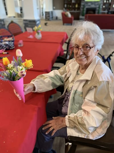 Resident smiling with a flower bouquet at a table