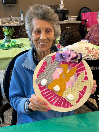 A resident showcasing a craft project in an activity room