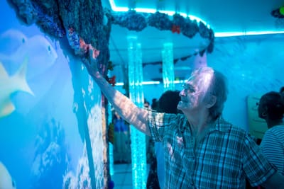 Resident interacting with a colorful sensory wall in a common area