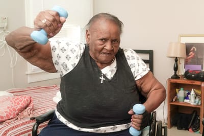 Senior resident exercising with dumbbells in a room