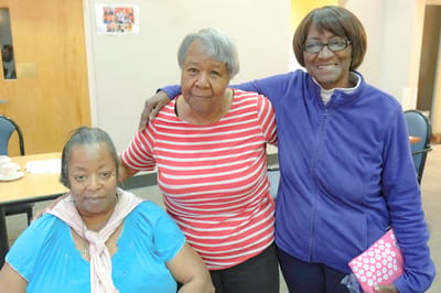 Three residents smiling together in a common area