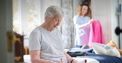 Resident enjoying a quiet moment while staff helps in the background