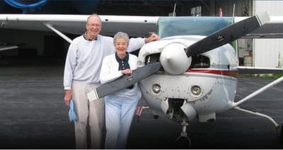 Couple posing with a small airplane at an airfield