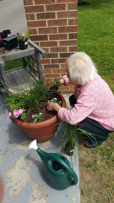 Resident planting flowers in a garden area