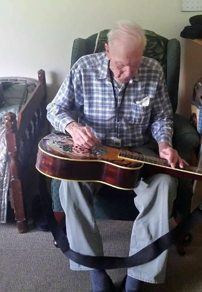 Resident playing guitar in a cozy chair