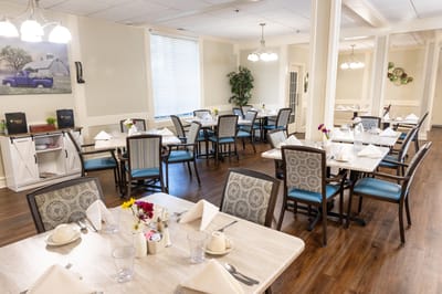 Bright dining room with neatly set tables and flowers