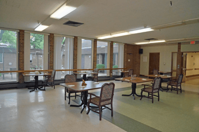 Dining area with tables and chairs, bright windows
