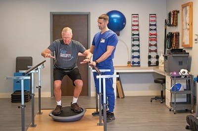 Therapist assisting a resident with balance exercise equipment