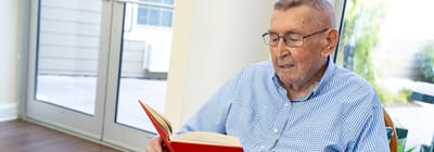 An elderly man reading a book in a cozy interior