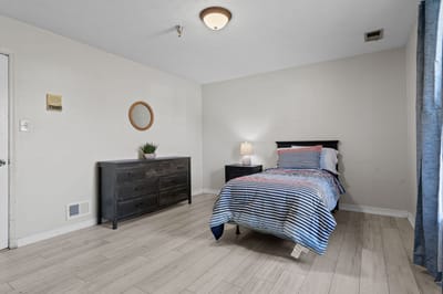 A well-furnished private resident room with a bed and dresser