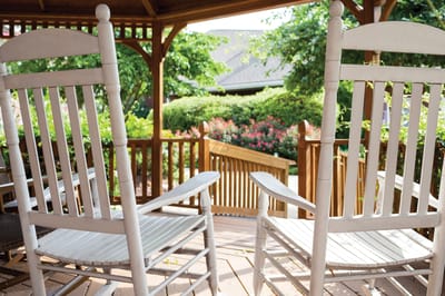 Rocking chairs on a porch surrounded by greenery