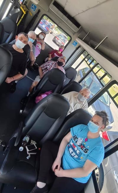 Residents and staff on a transport van, all wearing masks