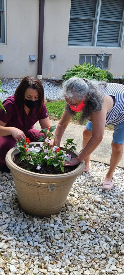Staff assisting a resident with gardening outdoors