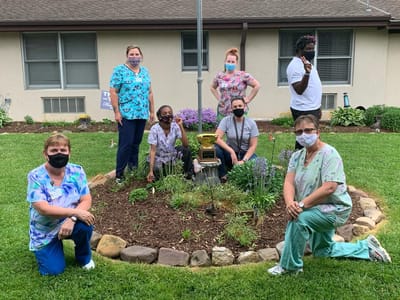 Staff members gathered in the garden with a trophy