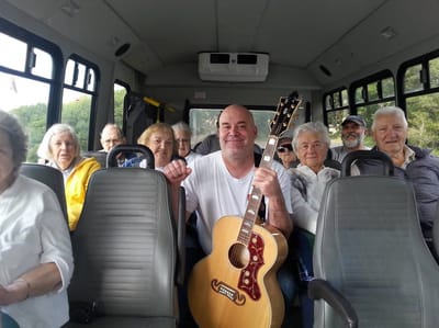 Residents enjoying a guitar performance on a facility bus
