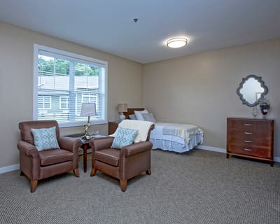 Bright private resident room with chairs and bed