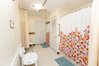 Bright bathroom with floral shower curtains and seating