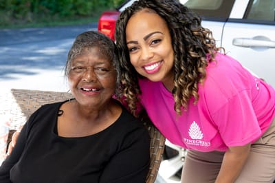 A resident smiling with staff member outdoors