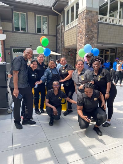 Staff posing together outside the facility with balloons