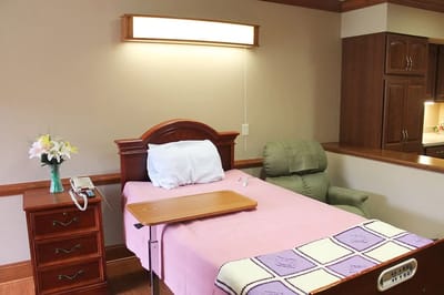 A private resident room with a bed and armchair