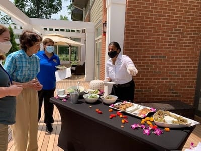 Residents enjoying a meal outdoors with staff