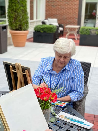 Resident painting in an outdoor area with flowers.