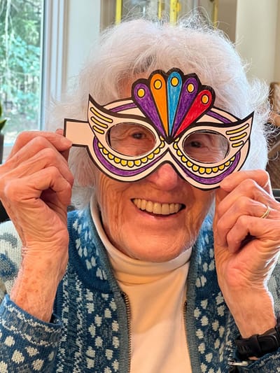Elderly woman wearing colorful craft glasses, smiling
