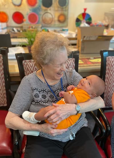 Resident joyfully holding a baby in a common area