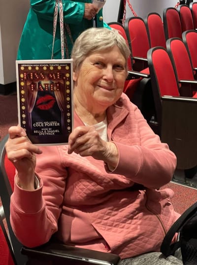 Resident holding a theater program in an audience seat