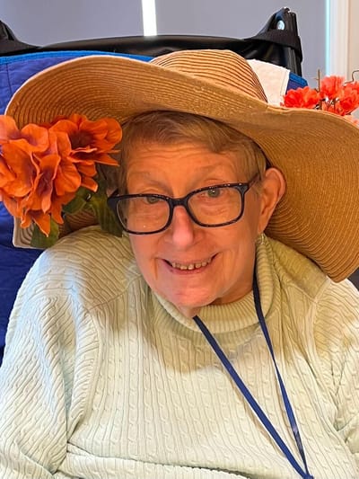 A resident smiling while wearing a large sun hat