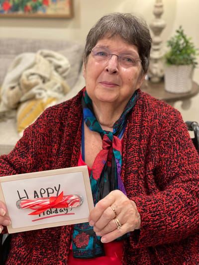 Resident holding a holiday card with a candy cane