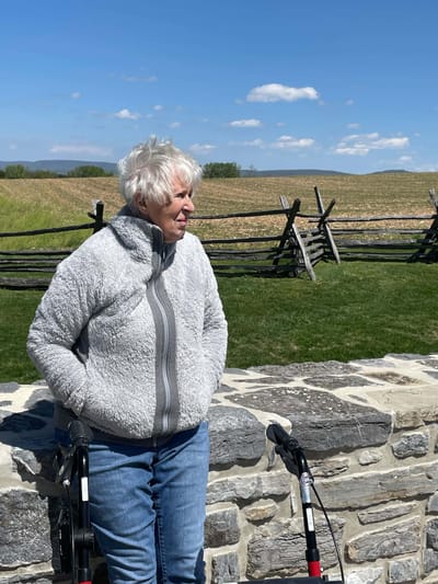 Elderly woman standing outdoors with walking aides