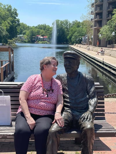 A resident interacting with a bronze statue by a water feature
