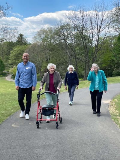 Residents and staff walking together on a paved path