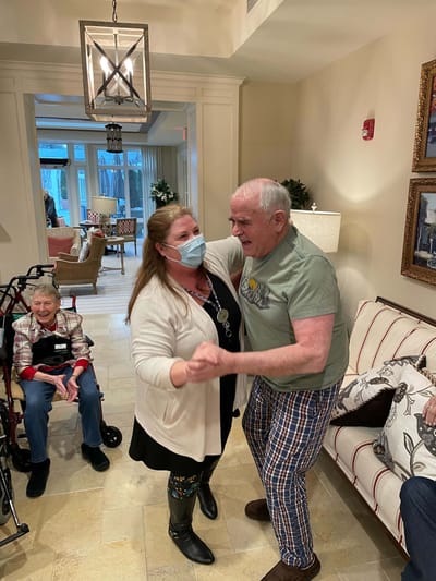 Residents and staff dancing in a lively common area