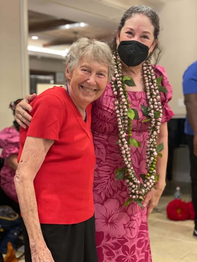 Residents and staff celebrating with leis inside the facility