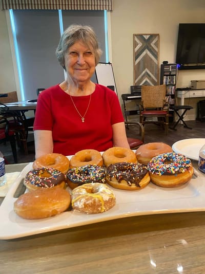 A resident smiling with a platter of donuts.