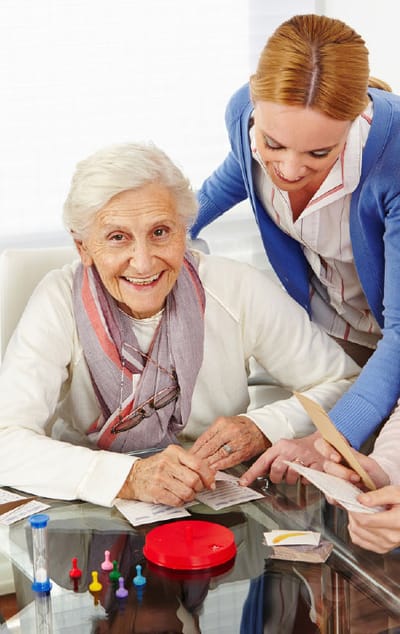 A senior woman engaging in an activity with staff assistance
