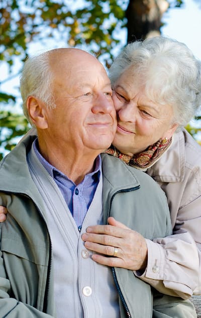 An elderly couple sharing a tender moment outdoors