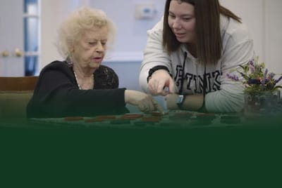 An elderly resident and staff member playing a game together