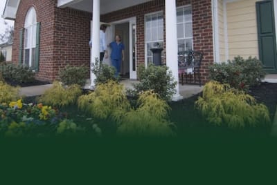A resident and staff member at the entrance of the facility