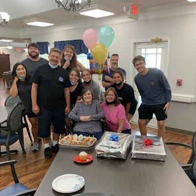 Residents and staff celebrating a birthday in a dining room