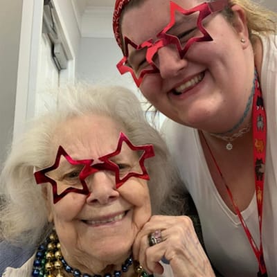 Resident and staff member smiling with star glasses