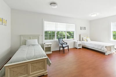 Bright shared resident room with two beds and a chair