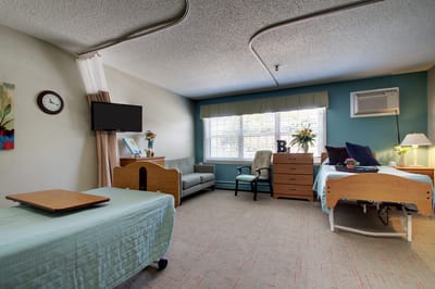 A cozy resident room with a bed and seating area