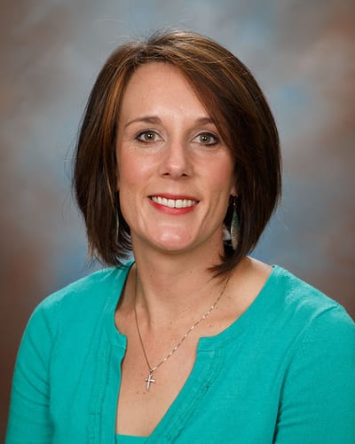 Portrait of a woman with brown hair wearing a turquoise sweater